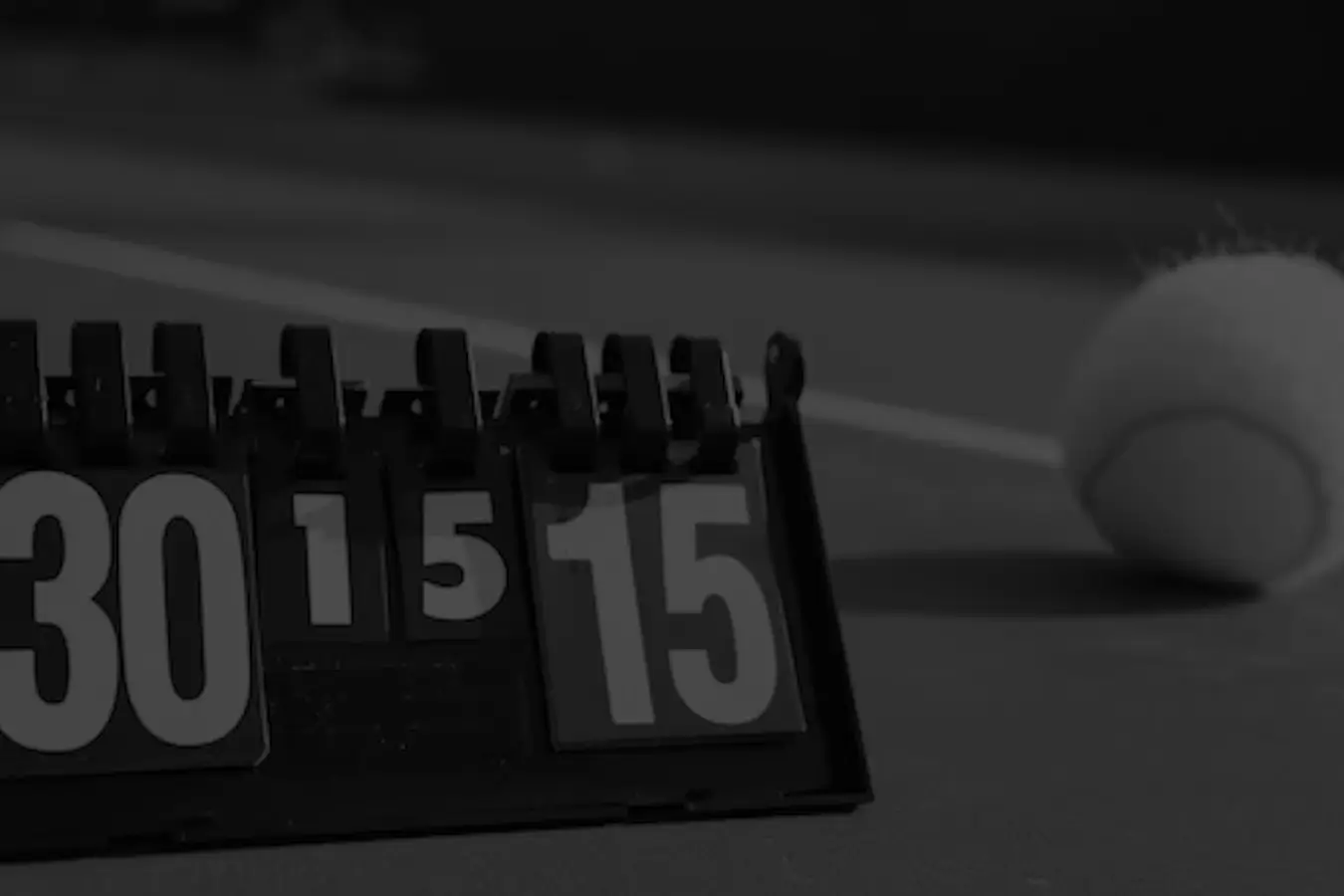 A black and white image of a tennis score counter showing 30-15, with a tennis ball on the court in the background.