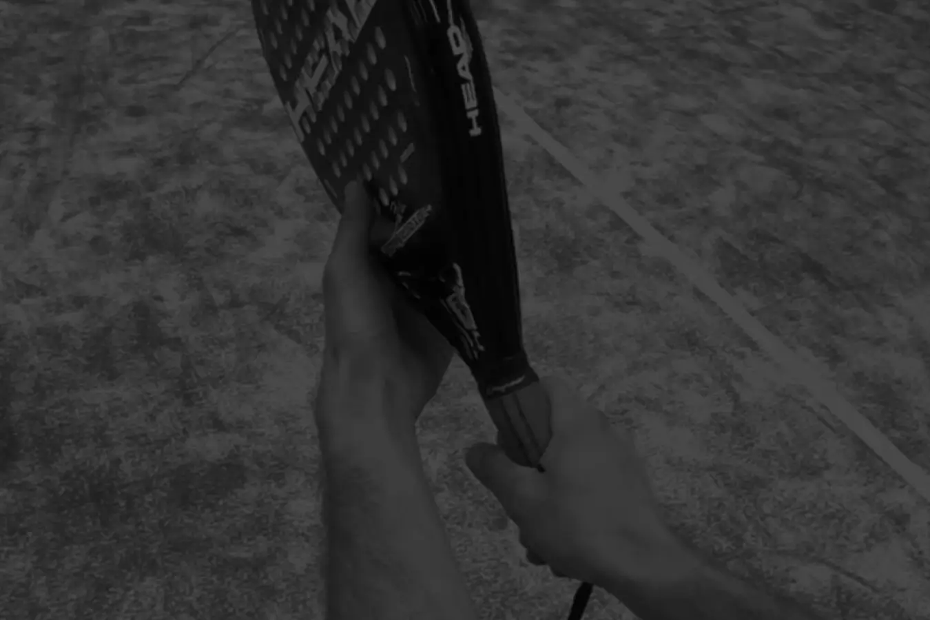 A person holding a padel racket using the continental grip on a padel court.