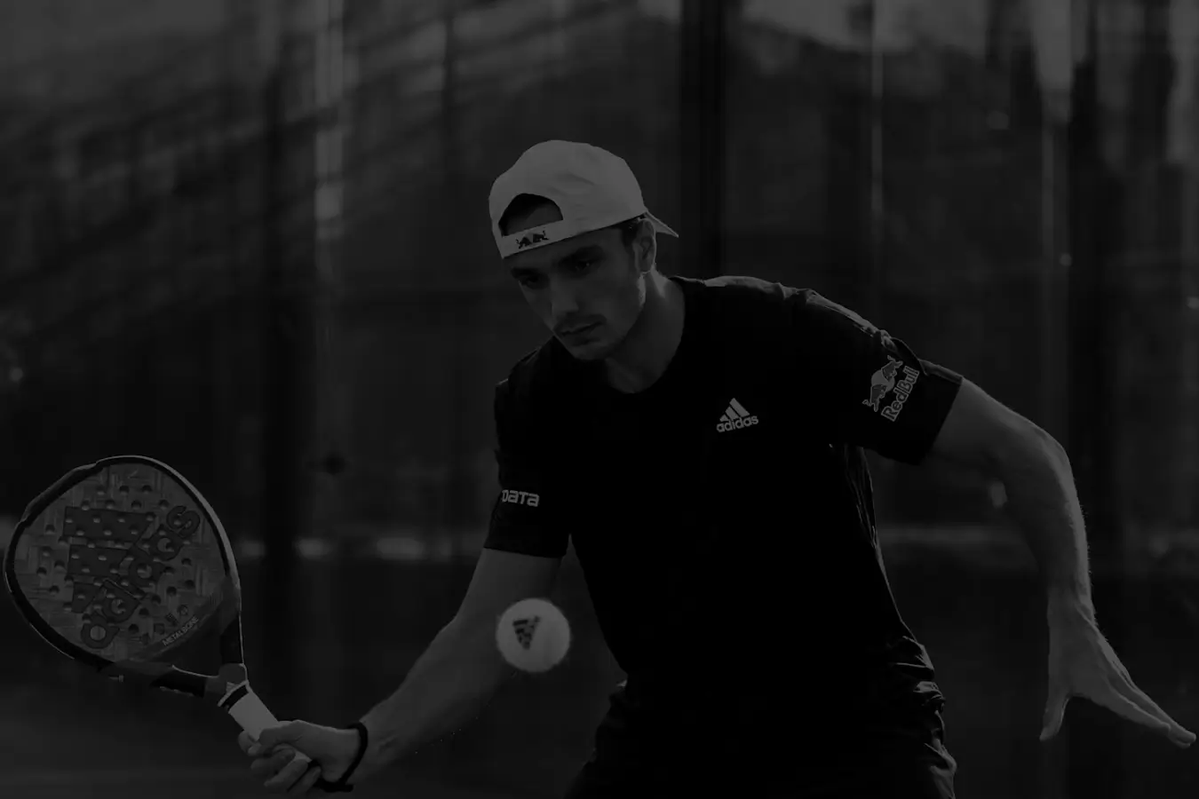 Alejandro Galán hitting the padel ball in black and white