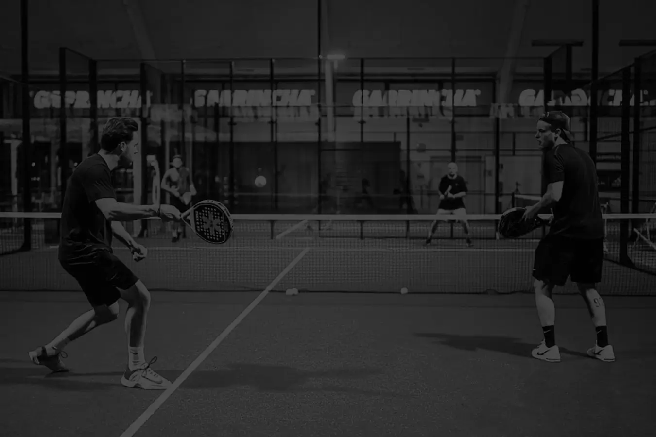 four players playing padel in black and white