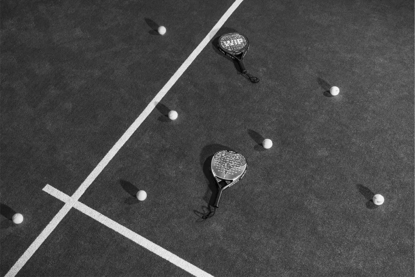 Padel rackets and balls scattered on the court after an intense session, capturing the aftermath of a game in progress.