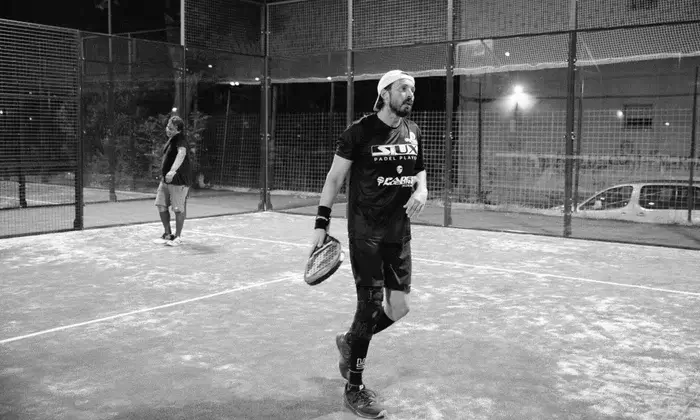 Padel player walking off the court after a match, holding a racket and wearing a focused expression.